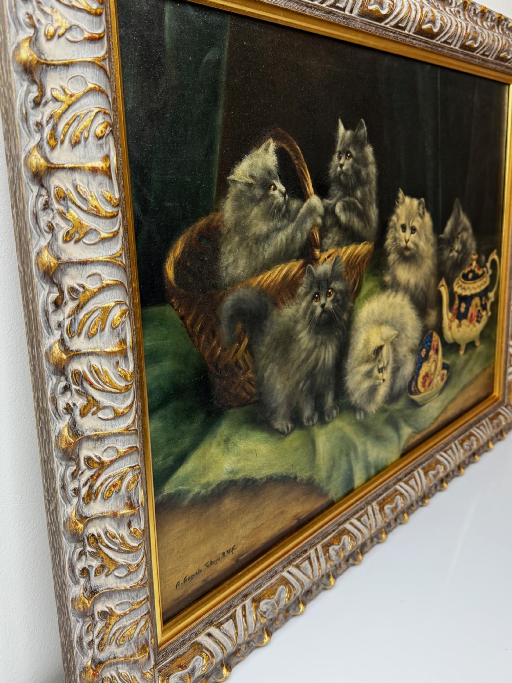 A framed oil painting featuring six fluffy grey and silver Persian kittens arranged around a woven basket and a decorated porcelain teapot. View VI
