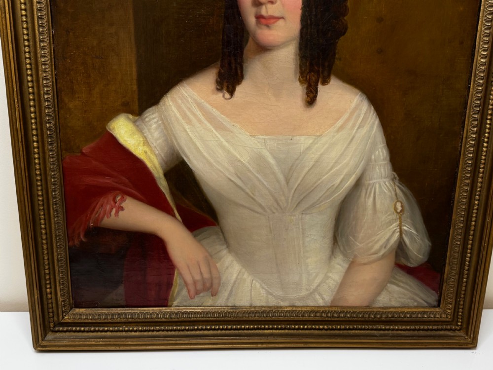An antique Georgian oil portrait painting depicting a woman in a white off-the-shoulder gown with a red drape, framed in a beaded gold gilt frame. View VII