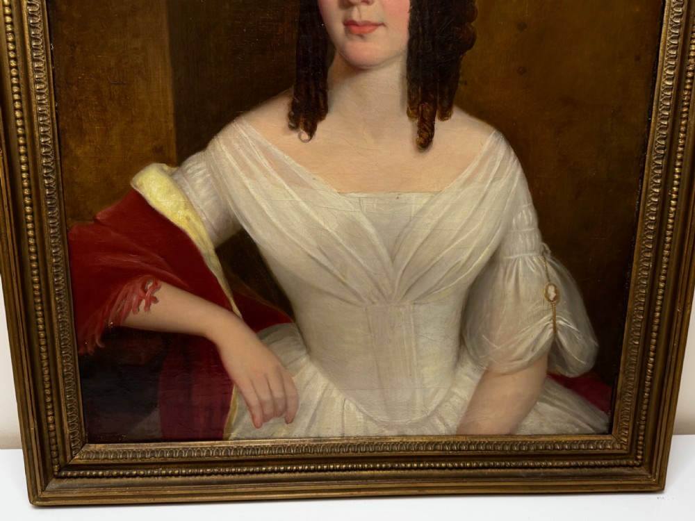 An antique Georgian oil portrait painting depicting a woman in a white off-the-shoulder gown with a red drape, framed in a beaded gold gilt frame. View VIII