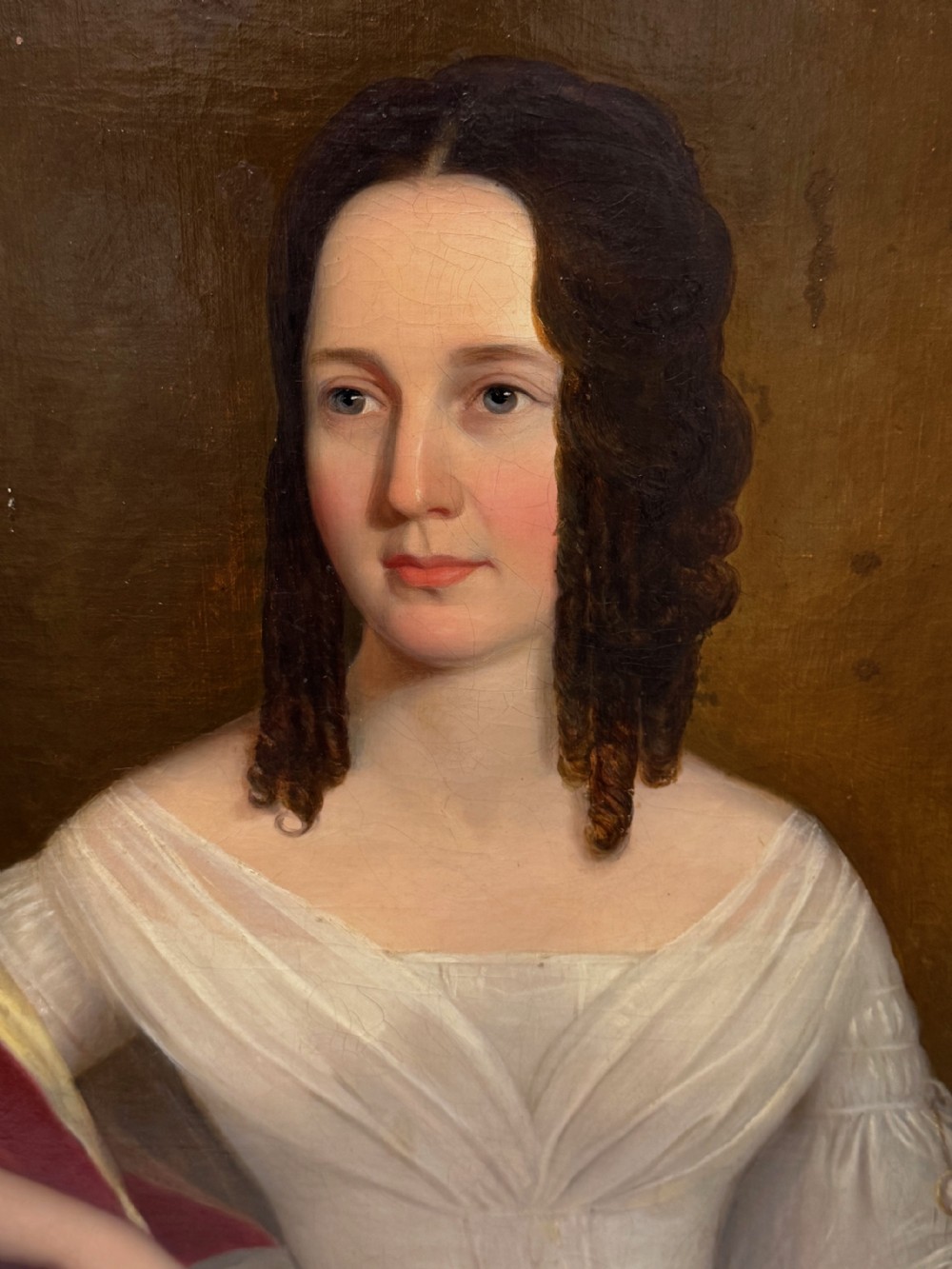 An antique Georgian oil portrait painting depicting a woman in a white off-the-shoulder gown with a red drape, framed in a beaded gold gilt frame. View XV