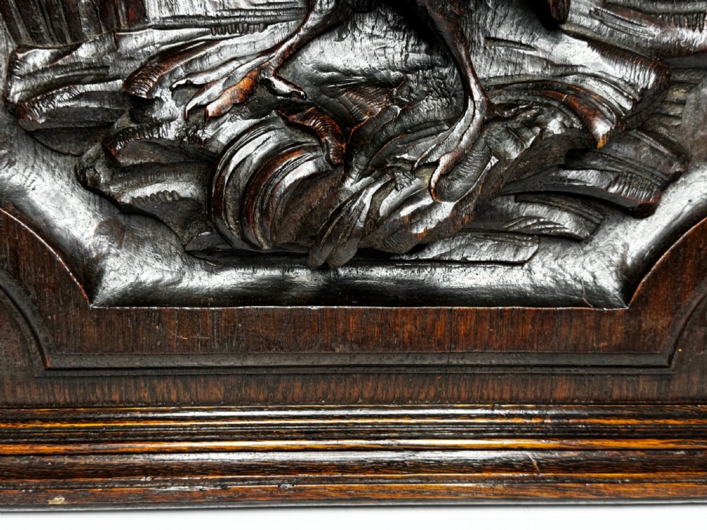 A dark oak relief carving depicting a game bird standing among reeds and oak leaves with acorns inside a moulded frame. View VI