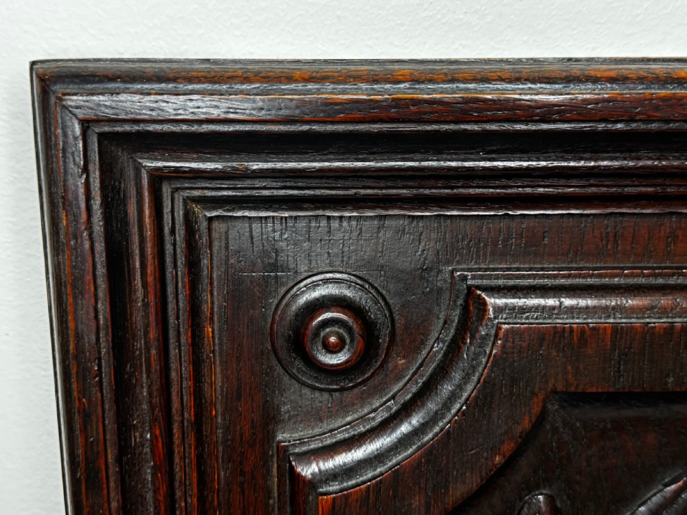 A dark oak relief carving depicting a game bird standing among reeds and oak leaves with acorns inside a moulded frame. View XXXI