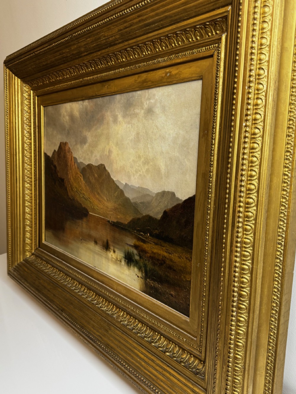A Victorian landscape oil painting depicting Lake Windermere with mountains in the background, set within a heavy multi-moulded gold frame. View XII