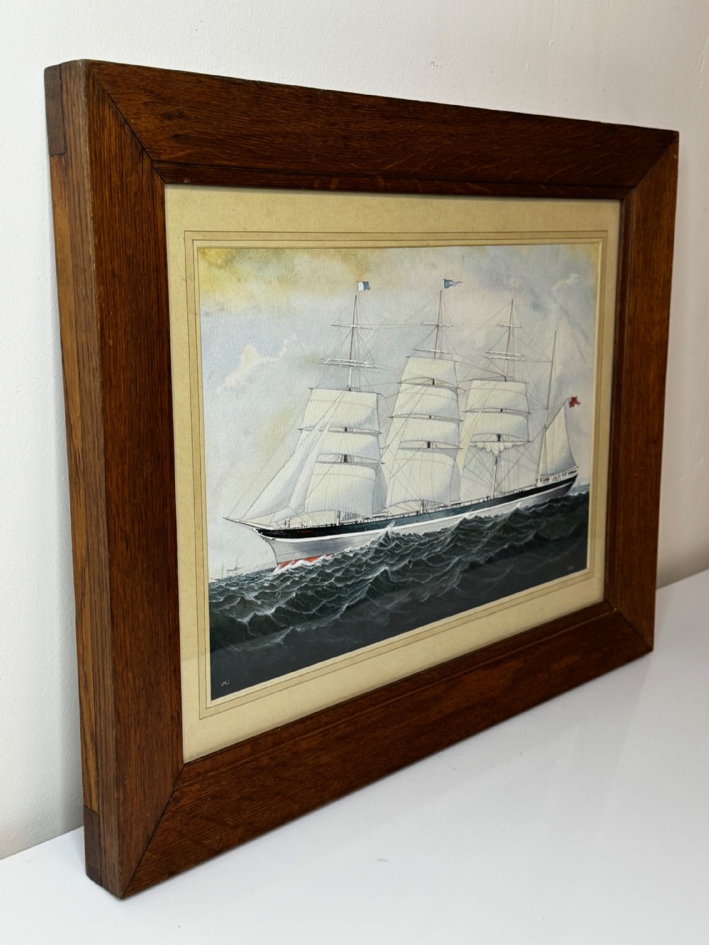 A framed maritime painting depicting a four-masted barque sailing ship on choppy water set within a light card mount and a wide wooden frame. View IV