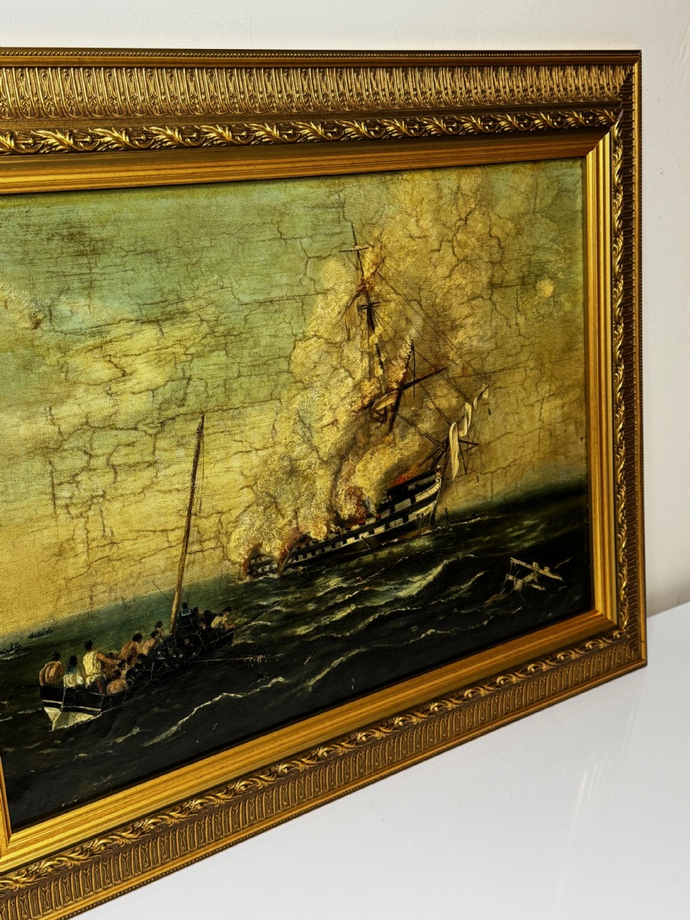 A framed 19th-century style maritime oil painting on canvas depicting a ship engulfed in flames on choppy seas, set within an ornate gilded frame. View III