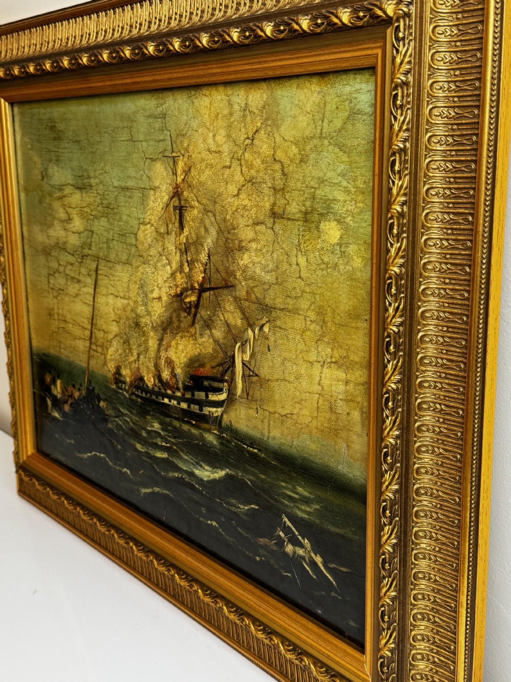 A framed 19th-century style maritime oil painting on canvas depicting a ship engulfed in flames on choppy seas, set within an ornate gilded frame. View IV