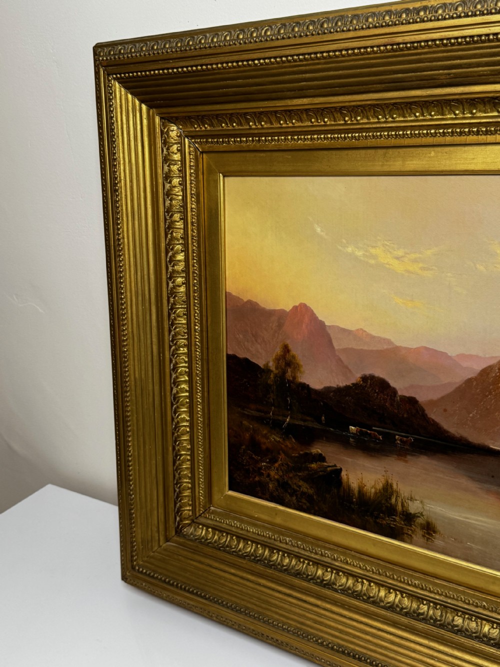 A Victorian oil painting depicting a lake landscape at sunset framed in a heavily moulded gilded frame. View III