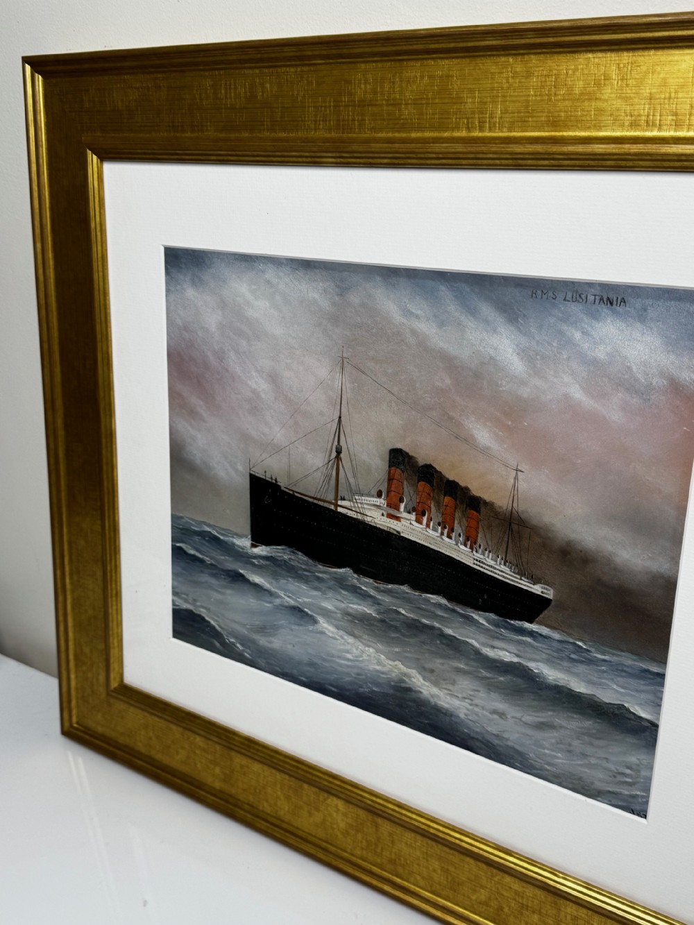 A framed marine painting depicting the RMS Lusitania ocean liner navigating choppy seas under a cloudy sky, enclosed within a textured gilt frame. View II