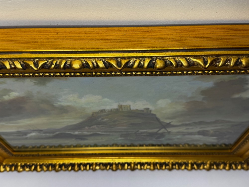 A Victorian oil painting depicting a coastal shipwreck near Bamburgh Castle under a cloudy sky, enclosed in a heavily gilded frame. View VII