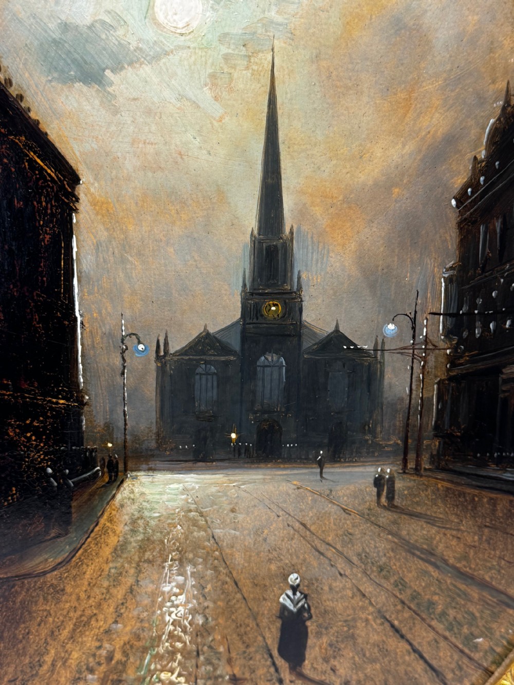 An oval Victorian oil painting depicting a wet night street lit by moonlight leading towards a church spire, framed in a carved gilt frame. View XII