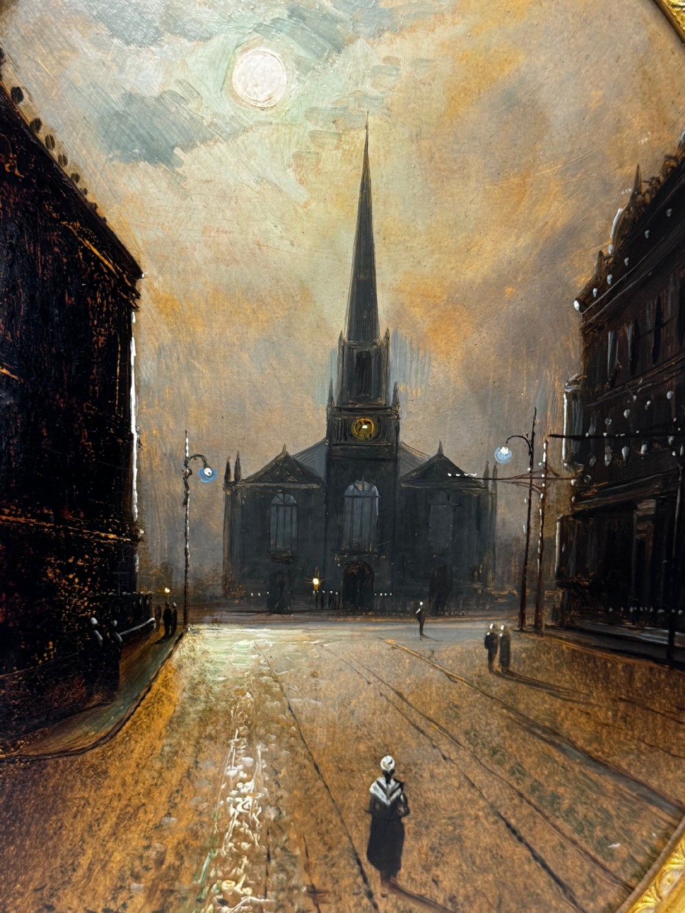 An oval Victorian oil painting depicting a wet night street lit by moonlight leading towards a church spire, framed in a carved gilt frame. View XIII