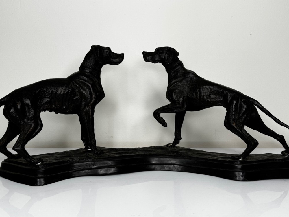 A dark patinated bronze sculpture depicting two hunting hound dogs in active poses on an integral naturalistic base. View II