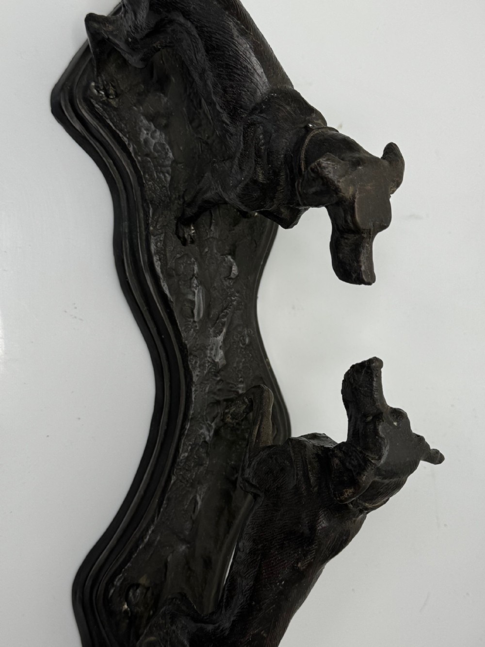 A dark patinated bronze sculpture depicting two hunting hound dogs in active poses on an integral naturalistic base. View VI