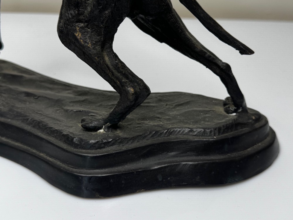 A dark patinated bronze sculpture depicting two hunting hound dogs in active poses on an integral naturalistic base. View VII