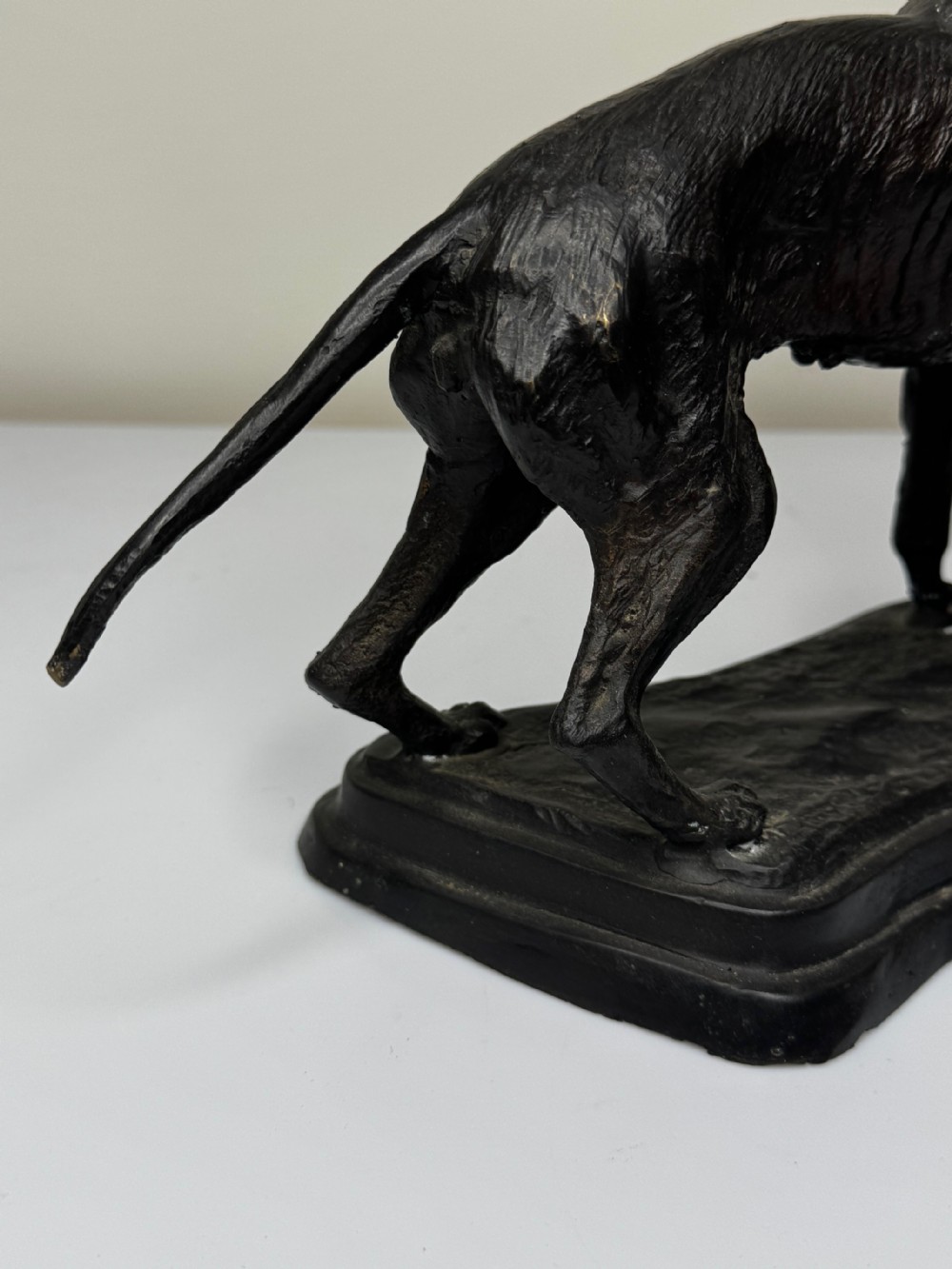 A dark patinated bronze sculpture depicting two hunting hound dogs in active poses on an integral naturalistic base. View VIII