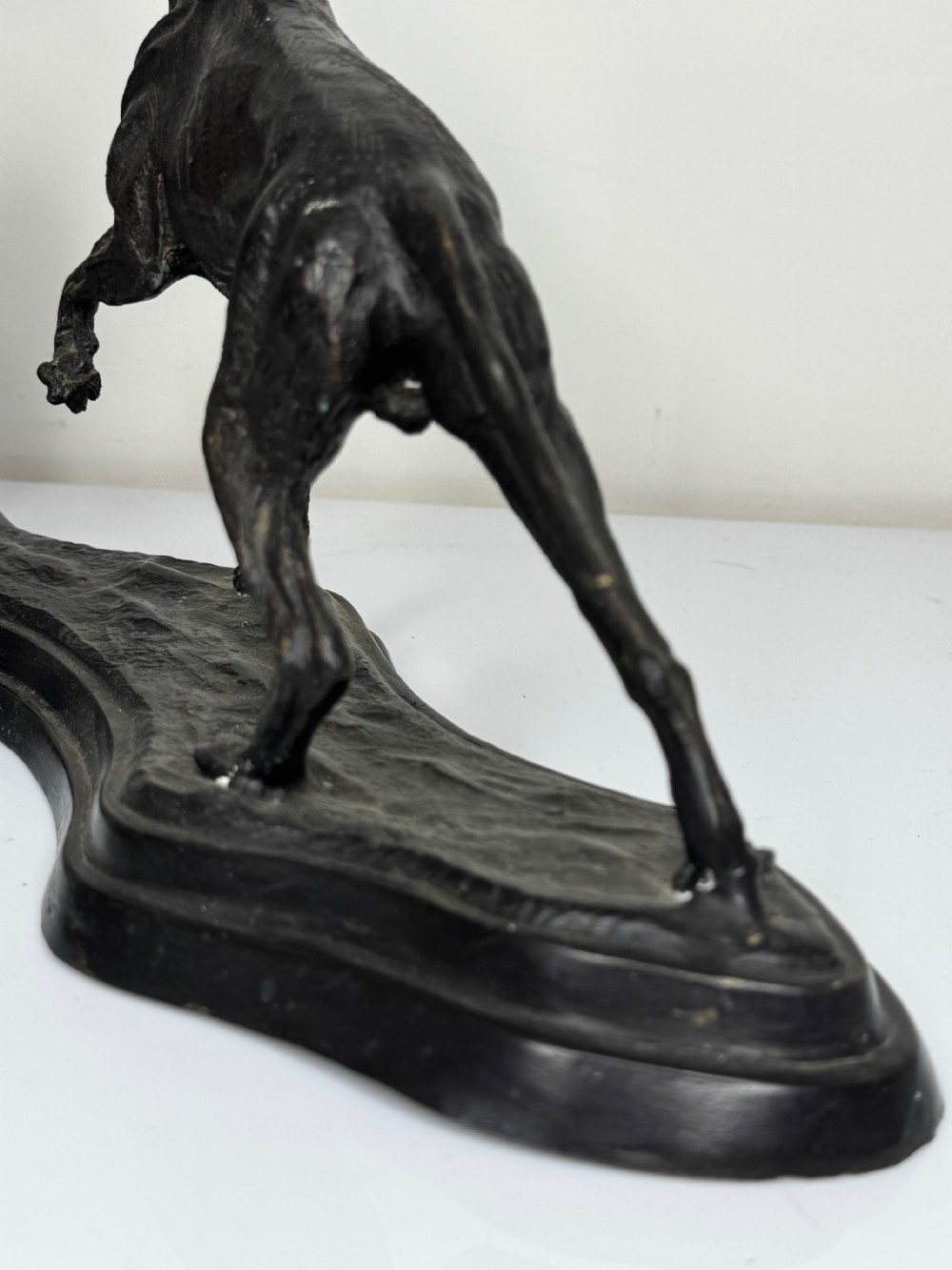 A dark patinated bronze sculpture depicting two hunting hound dogs in active poses on an integral naturalistic base. View XXVII