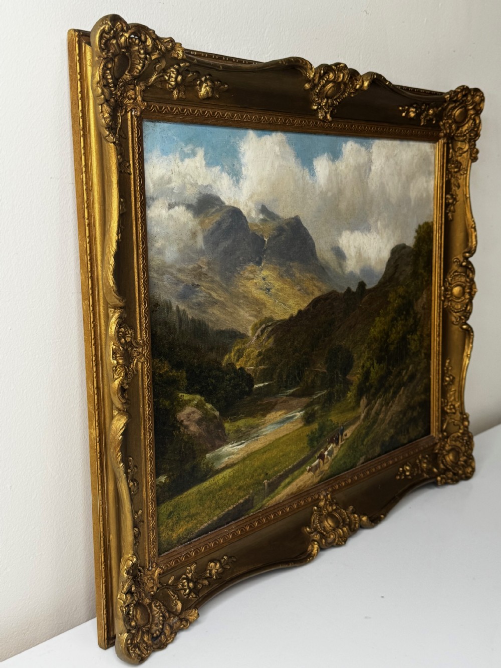 A Victorian landscape oil painting depicting the mountainous Borrowdale valley in the Lake District set within an ornate carved gold gilt frame. View IV