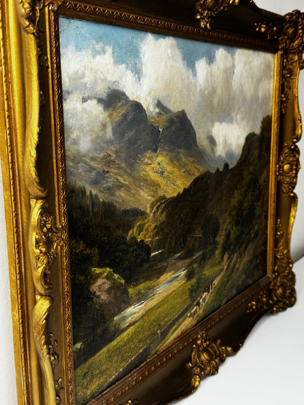 A Victorian landscape oil painting depicting the mountainous Borrowdale valley in the Lake District set within an ornate carved gold gilt frame. View VII