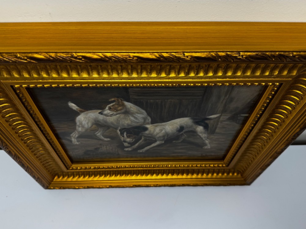 A 19th-century oil painting depicting two Jack Russell terriers standing near a caged rat inside a barn, housed in an ornate gold frame. View IX