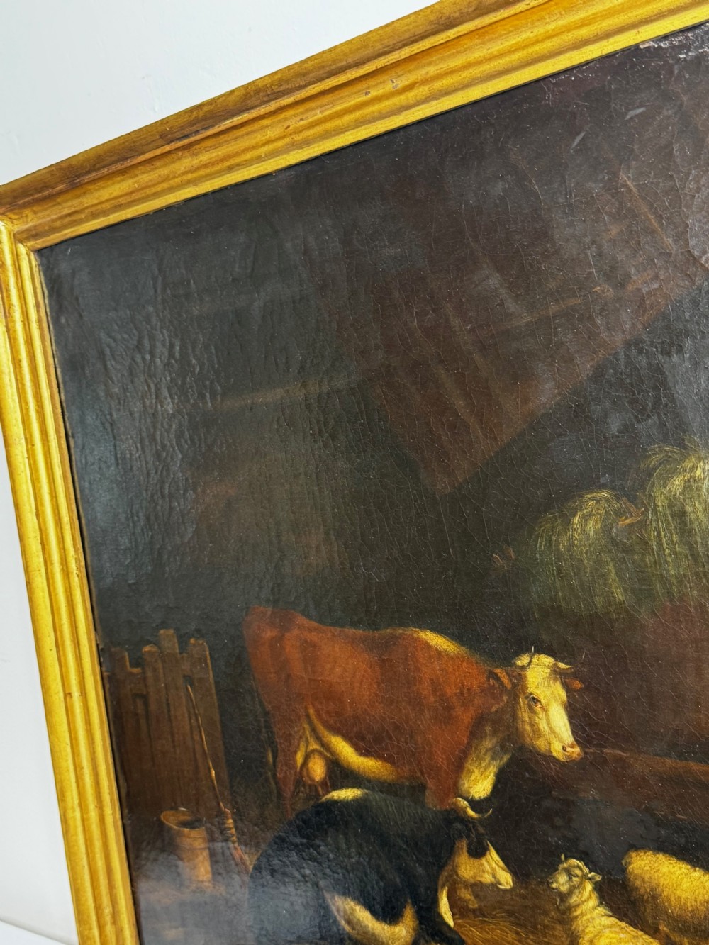 A 19th-century oil painting depicting cattle and sheep resting inside a dimly lit barn beside a hay rack and root vegetables on the floor. View XXVIII