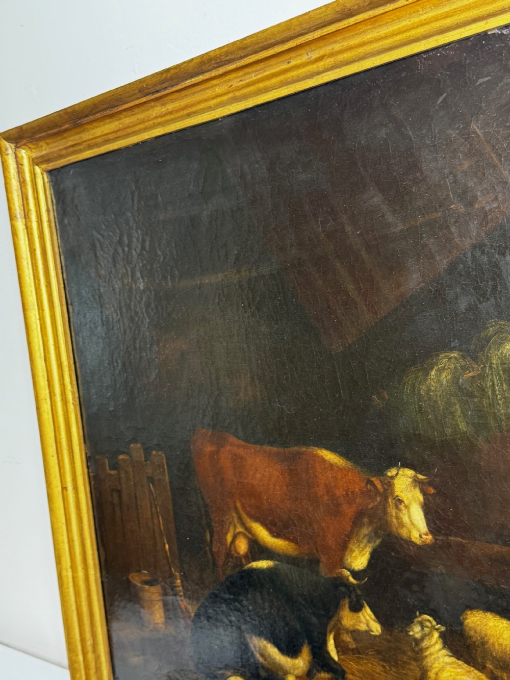 A 19th-century oil painting depicting cattle and sheep resting inside a dimly lit barn beside a hay rack and root vegetables on the floor. View XXIX