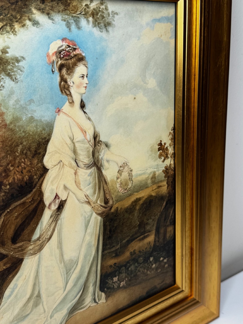 An eighteenth-century style portrait painting of a noblewoman in classical drapery holding a flower garland, displayed inside a wide gilded wooden frame. View XXVI