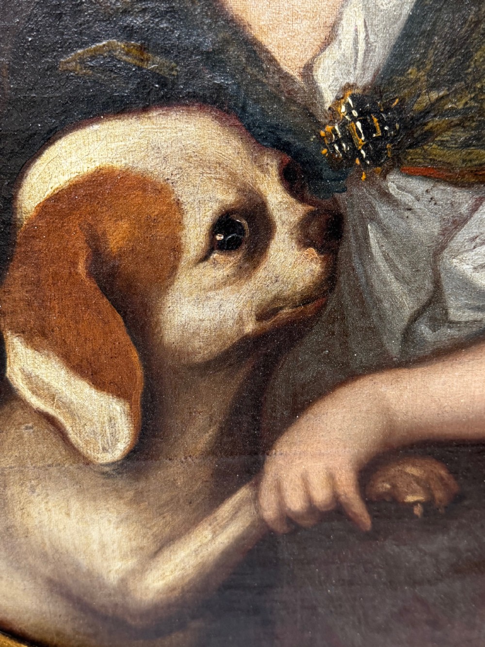 An oval seventeenth-century style oil portrait depicting a young child resting a hand on a King Charles Spaniel puppy, housed in a molded gilt frame. View V