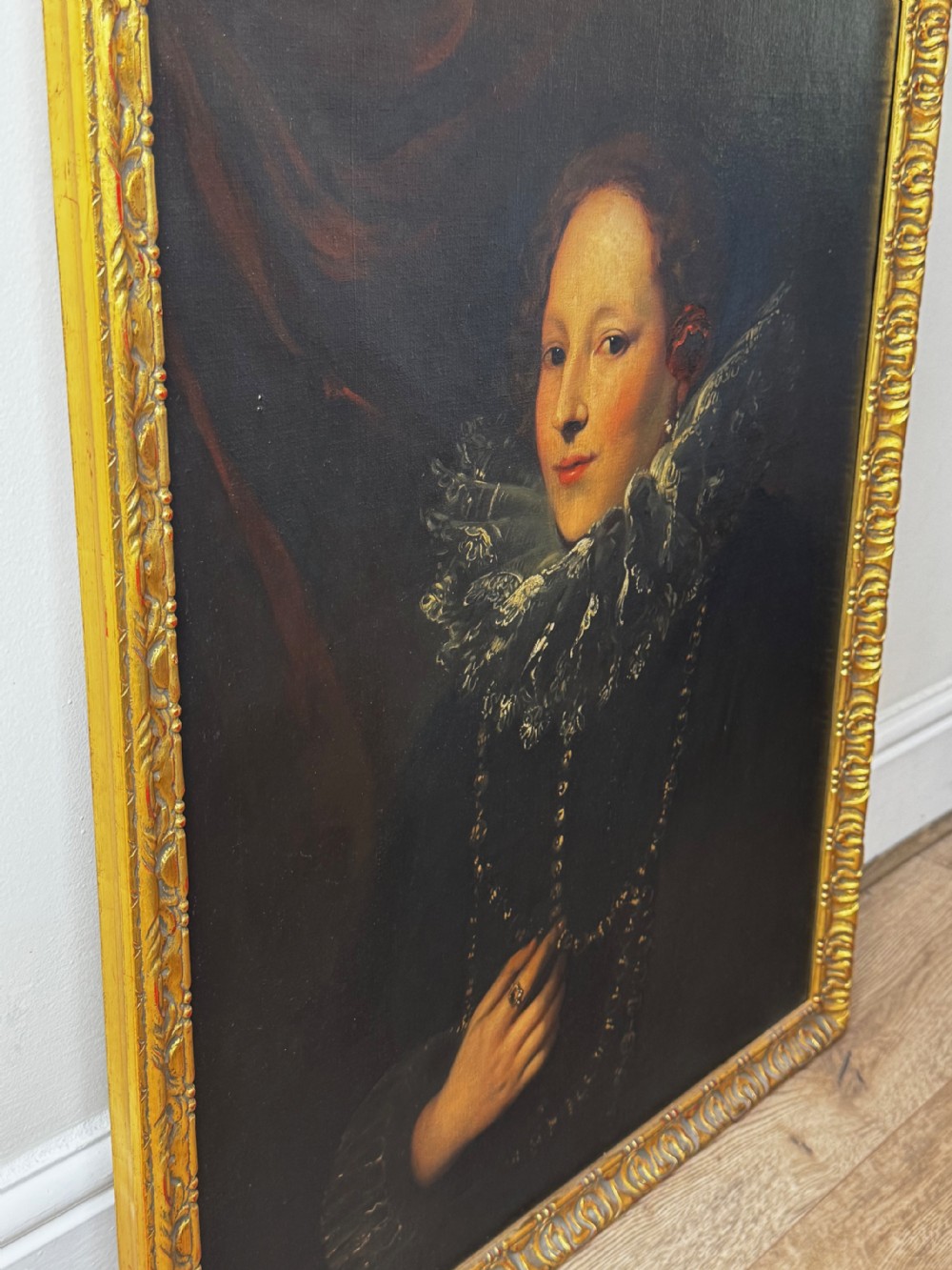 An oil painting depicting a lady in a black gown with a lace ruff collar and gold jewellery, set within an ornate carved giltwood frame. View III
