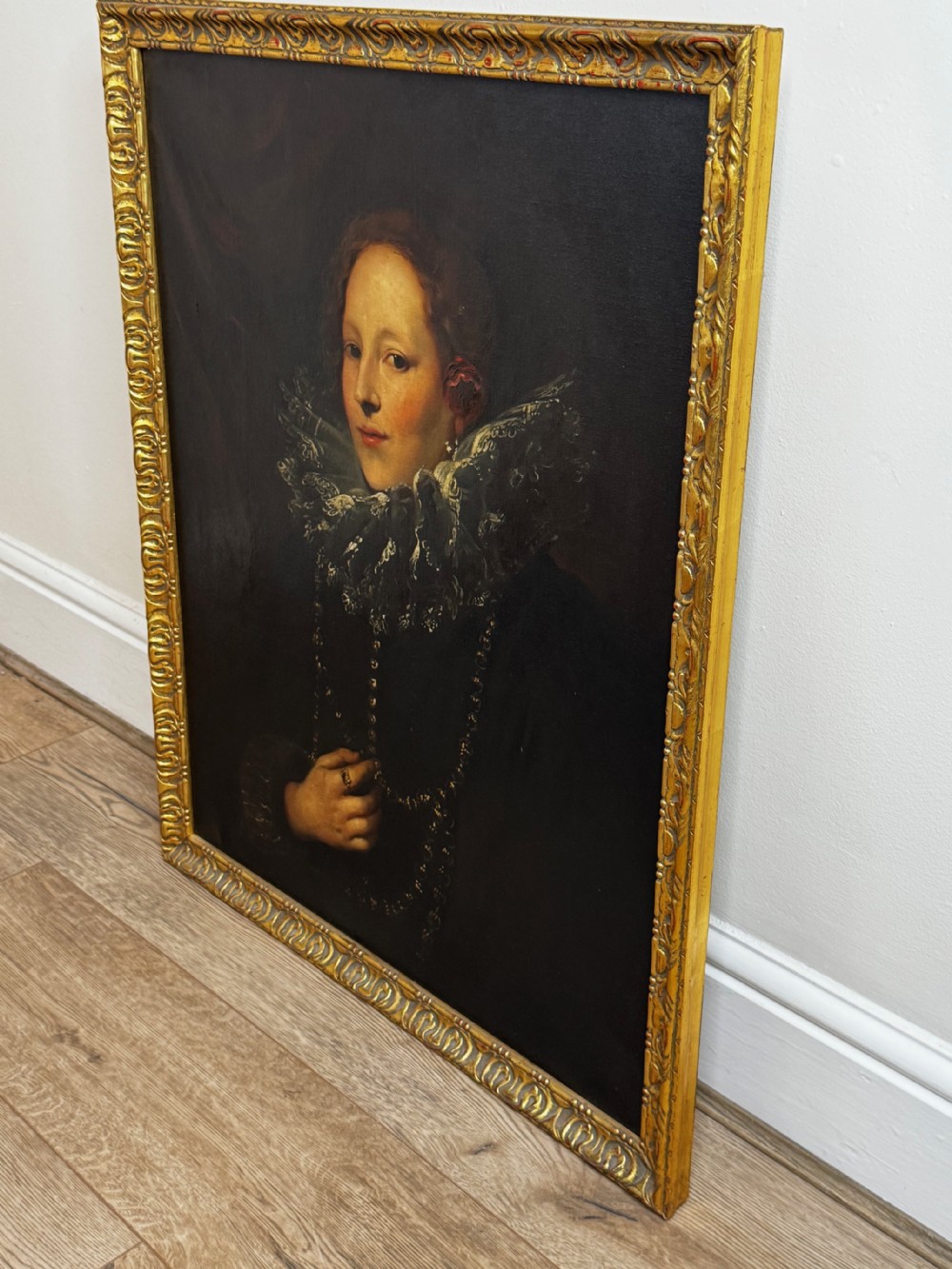 An oil painting depicting a lady in a black gown with a lace ruff collar and gold jewellery, set within an ornate carved giltwood frame. View IV