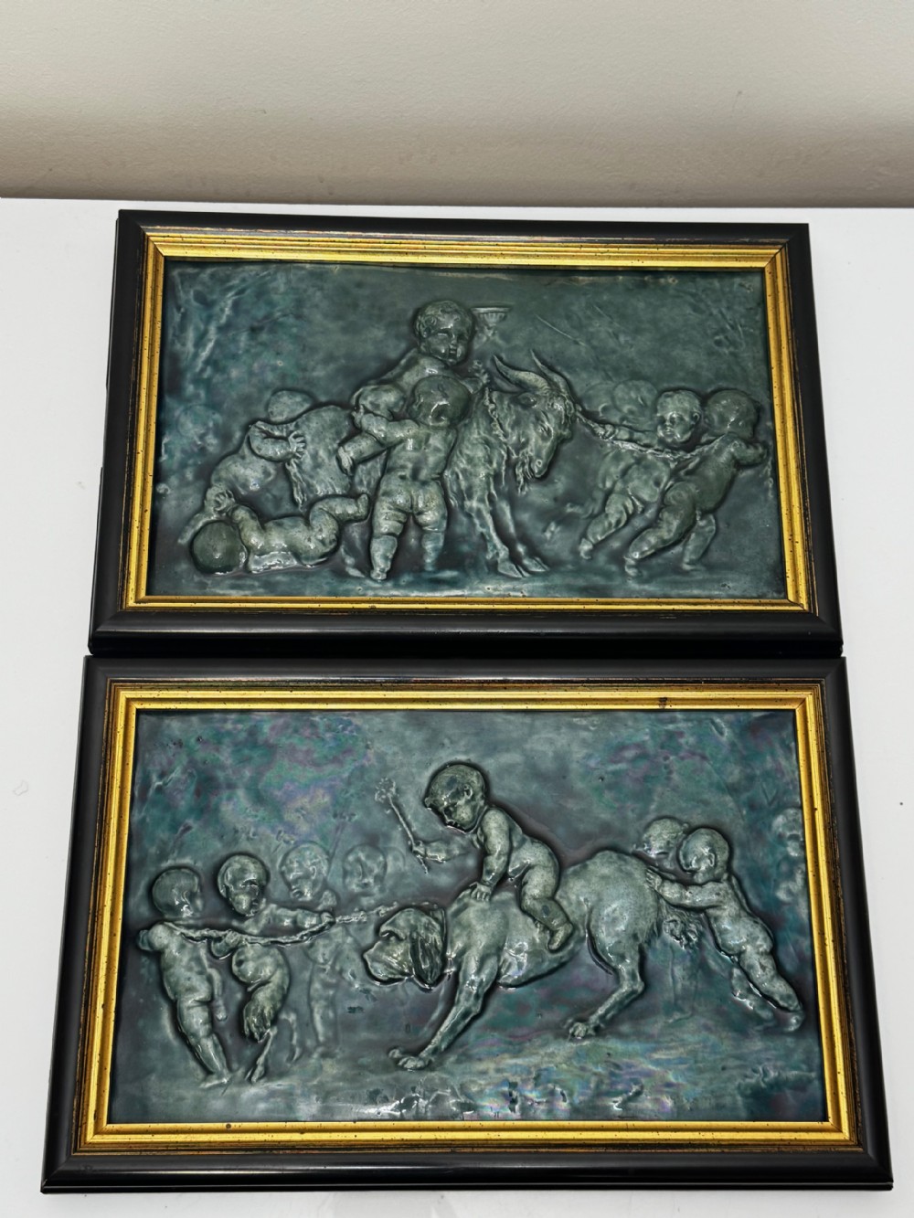 A pair of rectangular Arts and Crafts earthenware relief plaques with turquoise glaze displaying scenes of children with a goat and dog set in ebonised frames. View III