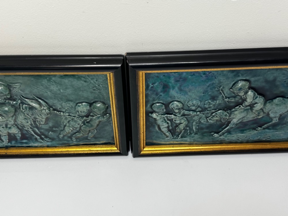 A pair of rectangular Arts and Crafts earthenware relief plaques with turquoise glaze displaying scenes of children with a goat and dog set in ebonised frames. View V