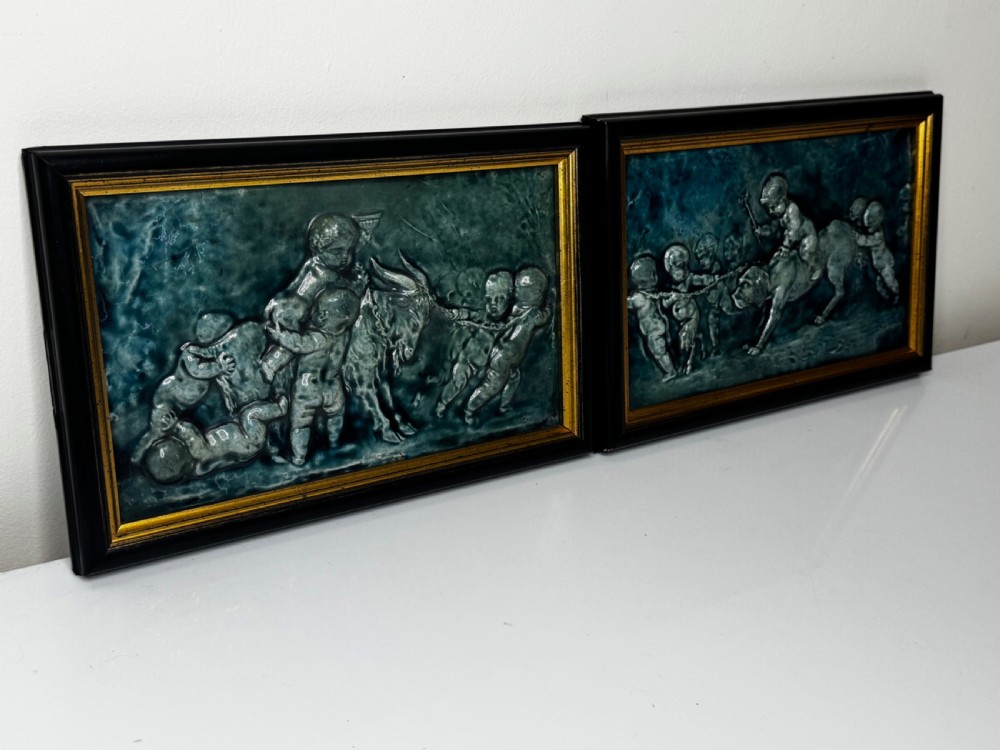 A pair of rectangular Arts and Crafts earthenware relief plaques with turquoise glaze displaying scenes of children with a goat and dog set in ebonised frames. View VII