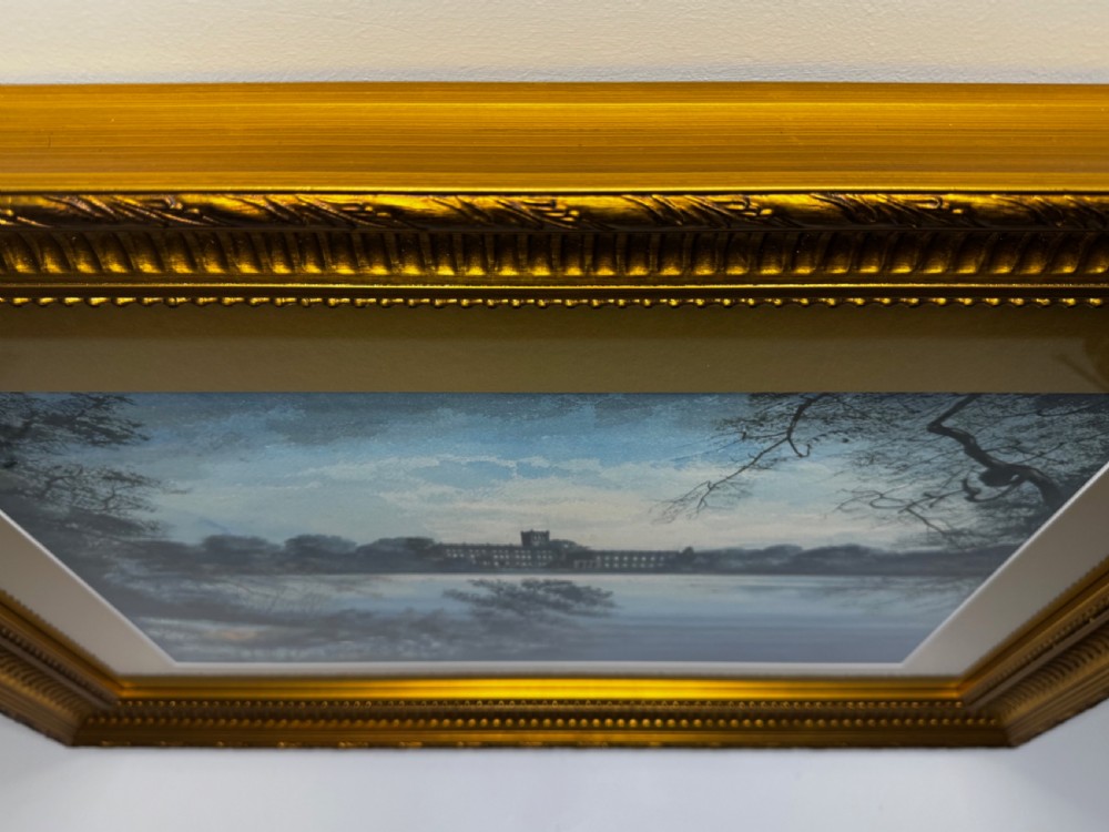 A framed landscape painting depicting Trentham Hall across a lake surrounded by trees, encased in a gold mount and ornate gilt frame. View IX