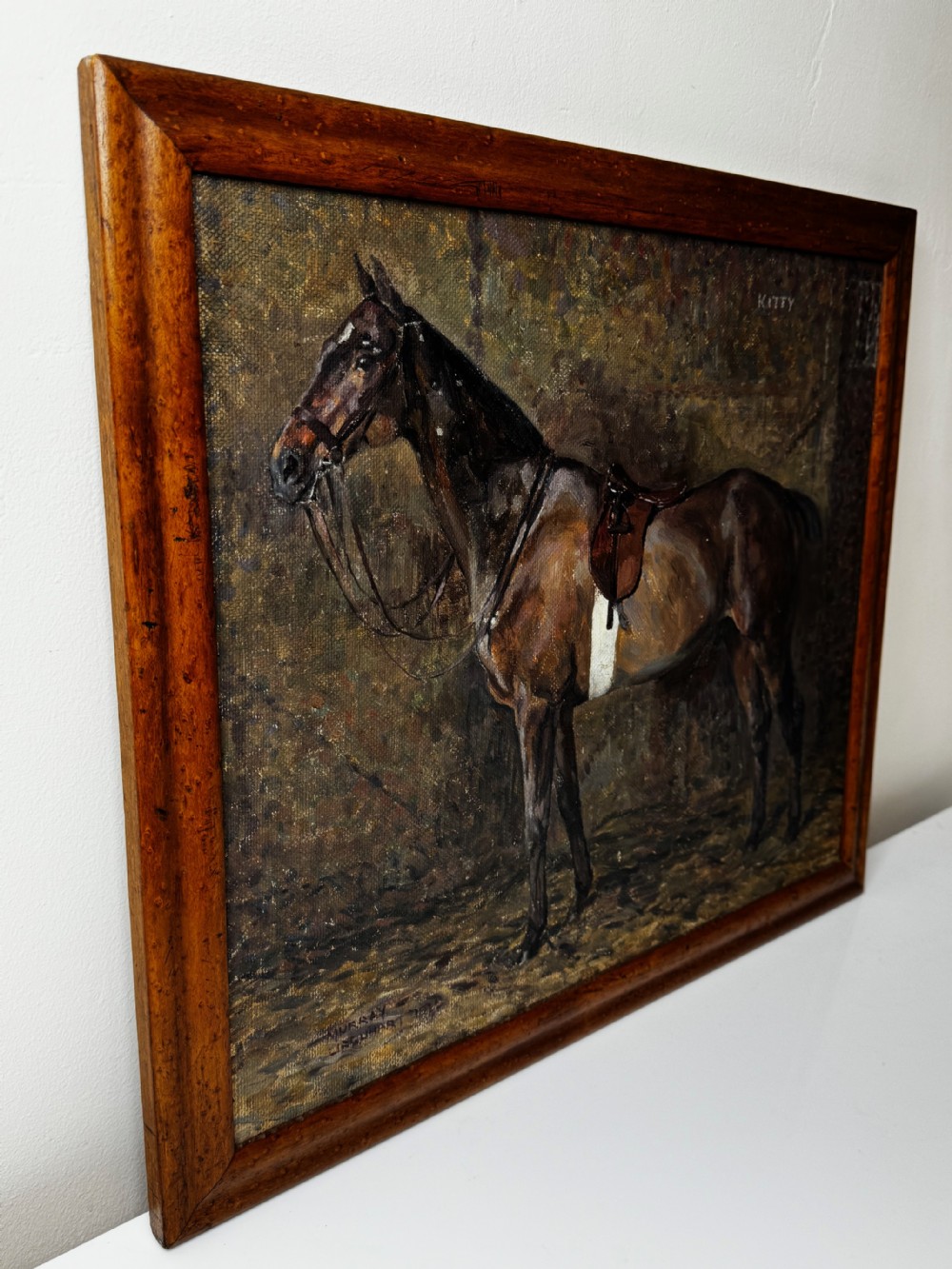 An oil painting framed in wood depicting a saddled brown hunter mare named Kitty standing in profile within a stable setting. View XIII