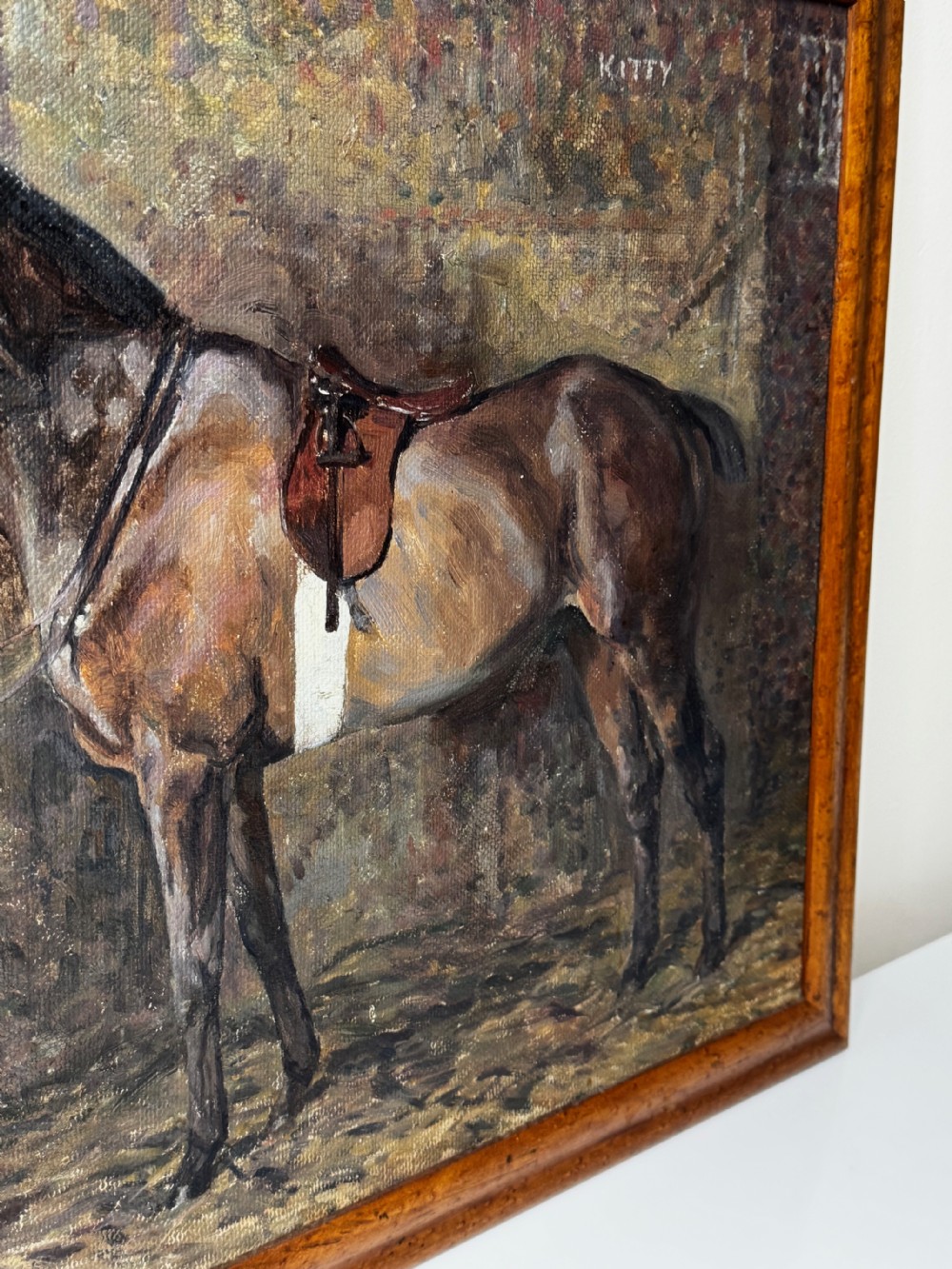 An oil painting framed in wood depicting a saddled brown hunter mare named Kitty standing in profile within a stable setting. View XIV