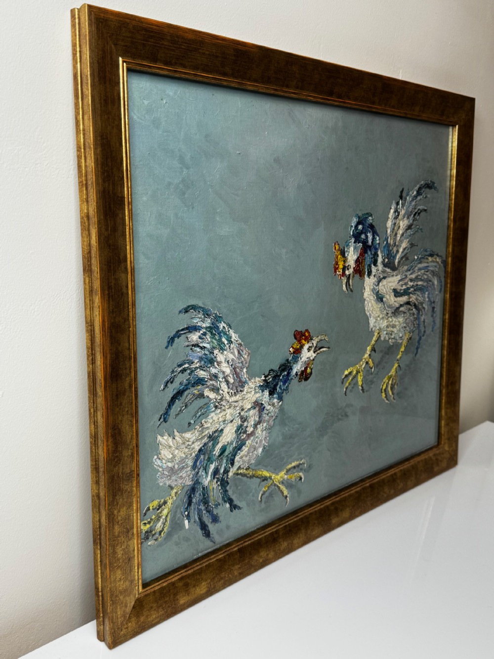 An expressionist impasto oil painting depicting two cockerels in motion against a blue-grey background within a gilt frame. View X