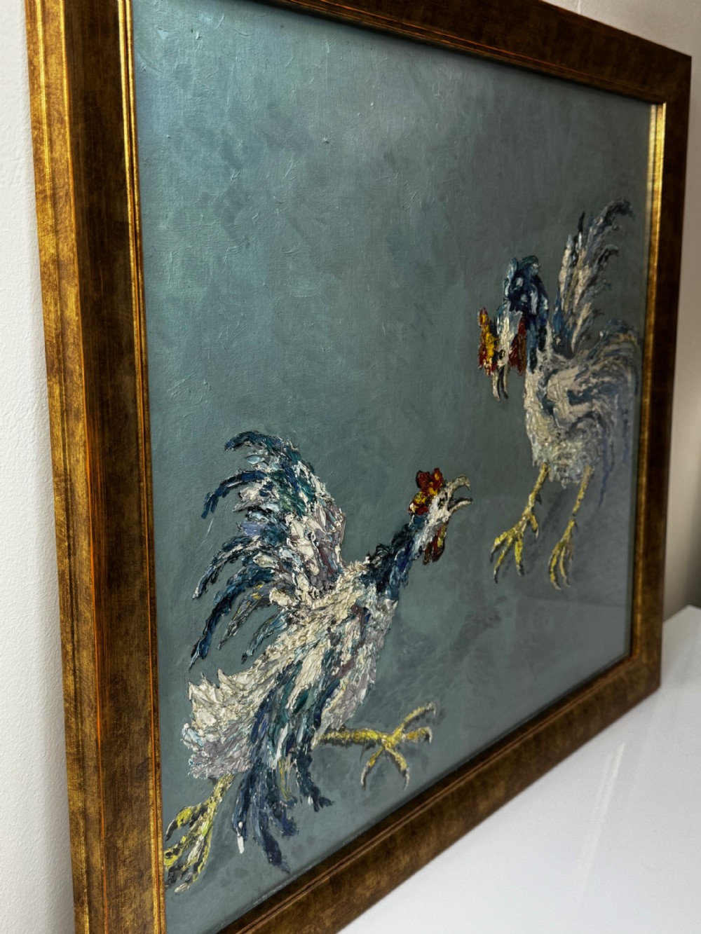 An expressionist impasto oil painting depicting two cockerels in motion against a blue-grey background within a gilt frame. View XI
