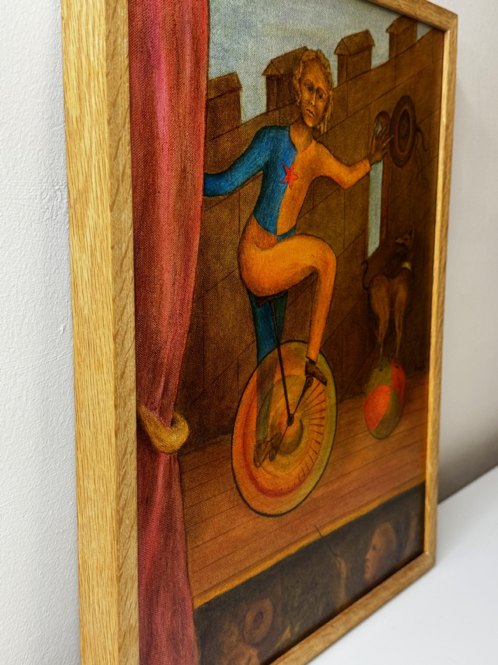 A framed Surrealist oil painting depicting a costume-clad performer on a unicycle next to a dog balancing on a sphere against a stone wall. View IX