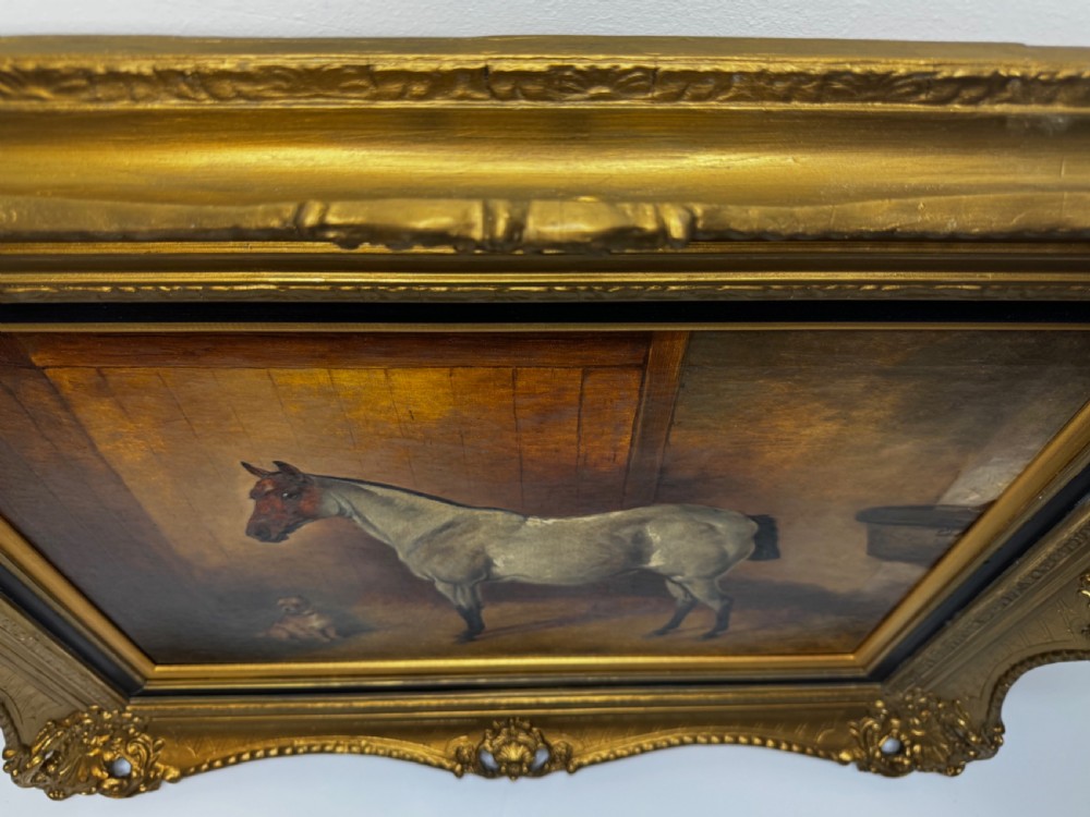 A Victorian oil painting depicting a grey roan horse and a small terrier inside a wooden stable, enclosed in a heavy gilded frame. View XXIX