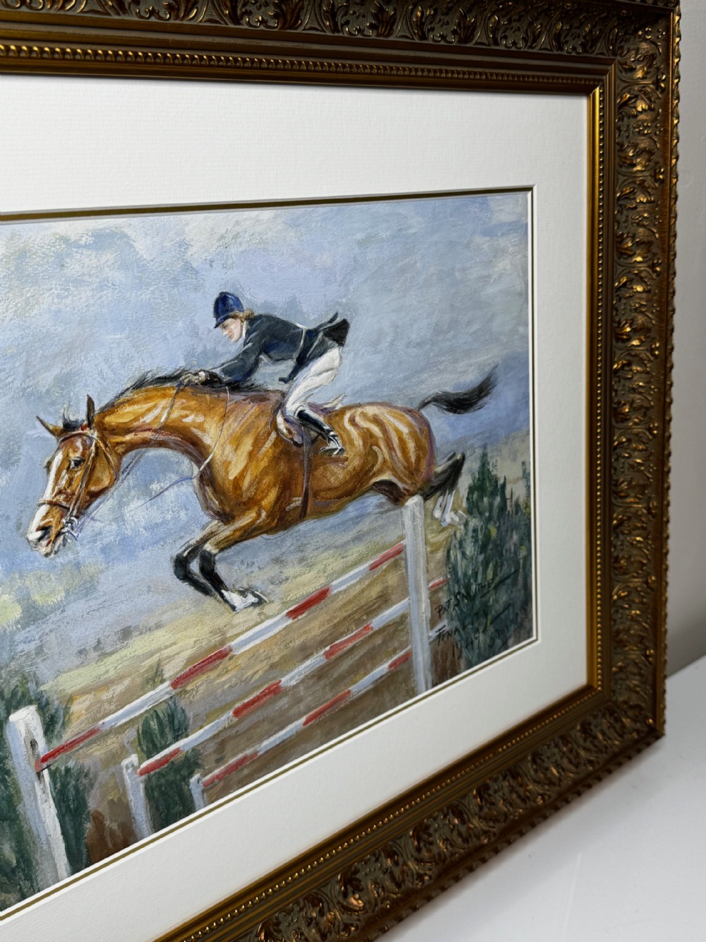 A framed oil painting depicting showjumper Pat Smythe on her horse Finality clearing a fence in 1949. View III