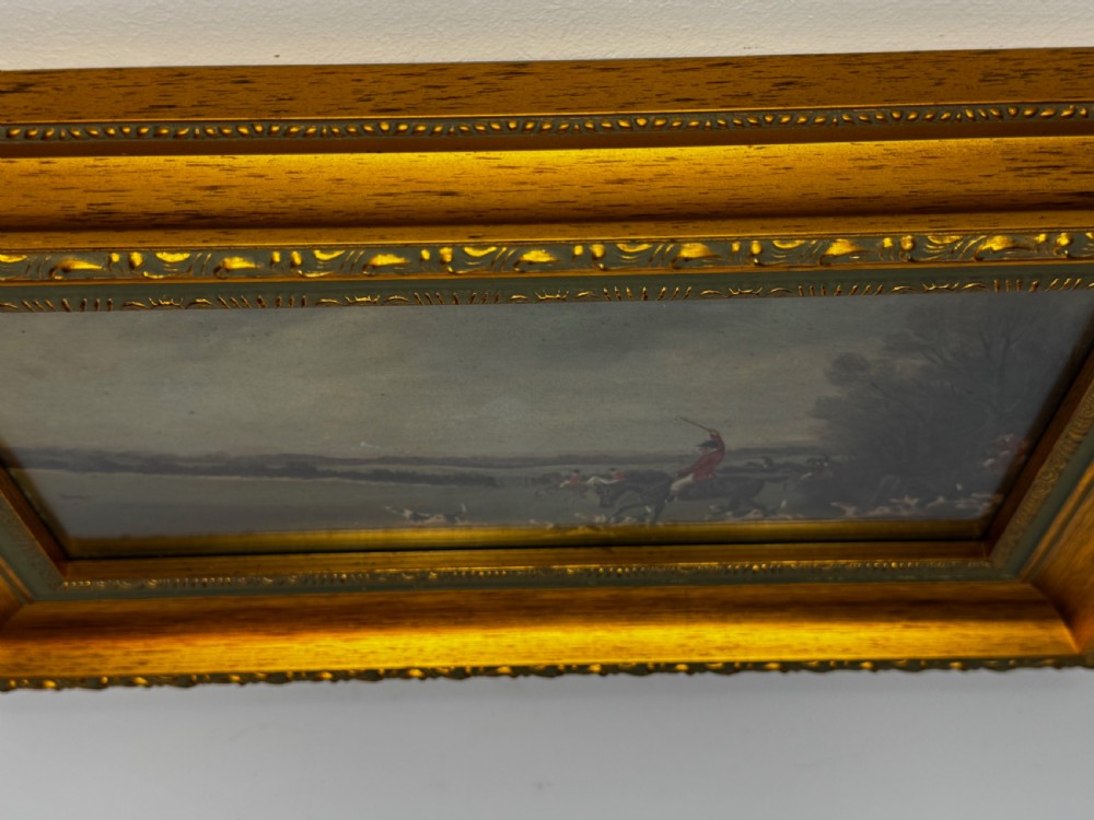 A 19th-century oil painting depicting a traditional fox hunting scene with huntsmen on horseback and hounds in an open landscape, enclosed in an ornate gilded frame. View V