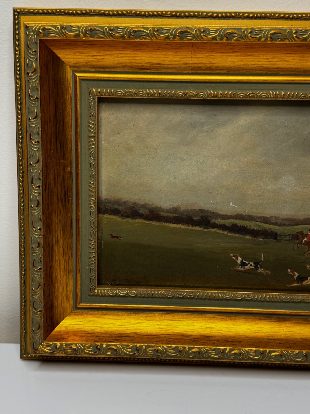 A 19th-century oil painting depicting a traditional fox hunting scene with huntsmen on horseback and hounds in an open landscape, enclosed in an ornate gilded frame. View VII