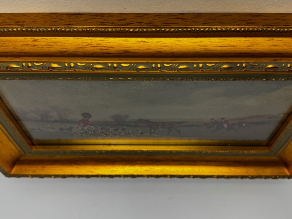 A Victorian oil painting depicting a fox hunting scene with huntsmen on horseback and a pack of hounds in a countryside landscape, housed in a gilded frame. View III