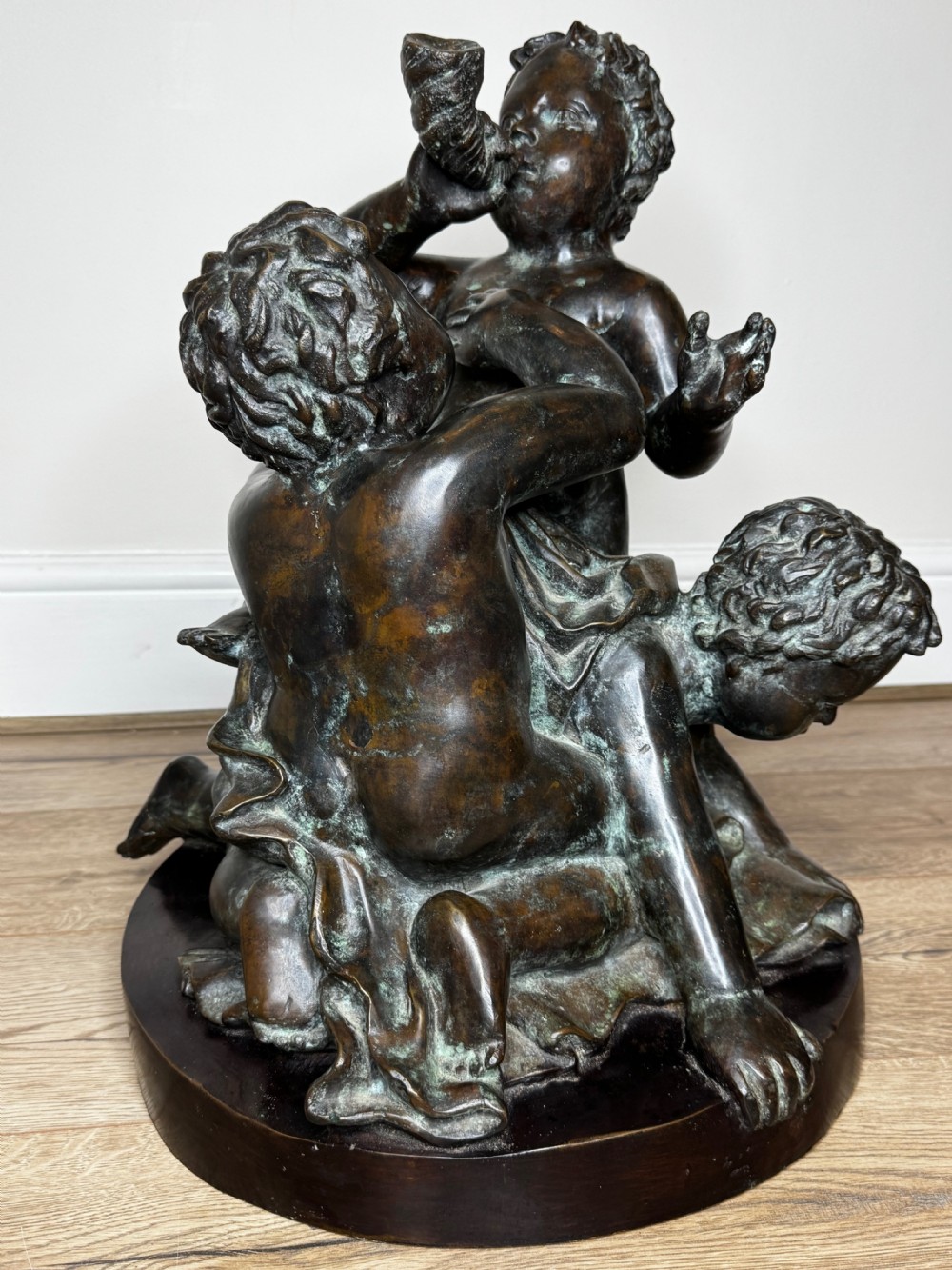 A dark patinated French bronze sculptural group depicting three putti playing, with one child blowing into a conch shell. View II