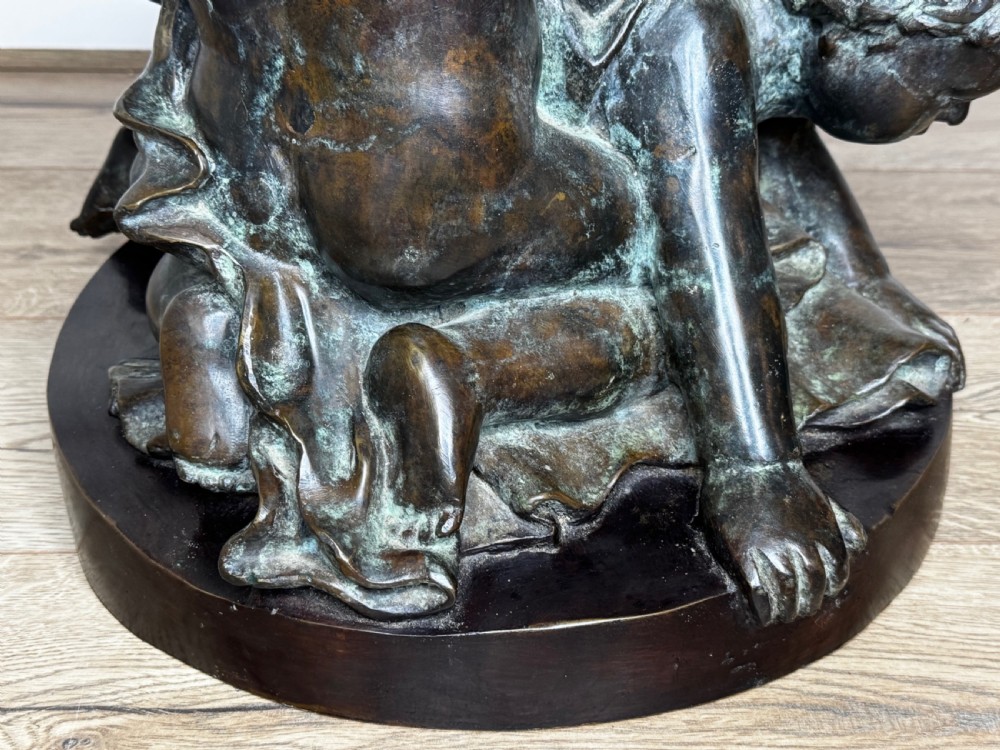 A dark patinated French bronze sculptural group depicting three putti playing, with one child blowing into a conch shell. View V