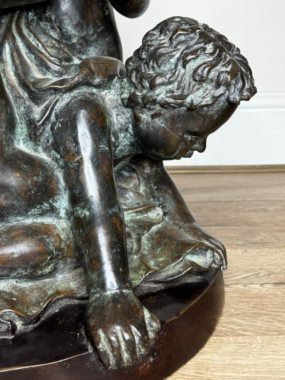 A dark patinated French bronze sculptural group depicting three putti playing, with one child blowing into a conch shell. View VII