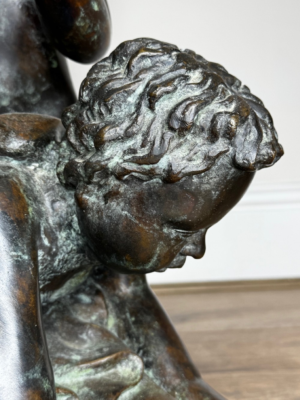 A dark patinated French bronze sculptural group depicting three putti playing, with one child blowing into a conch shell. View IX