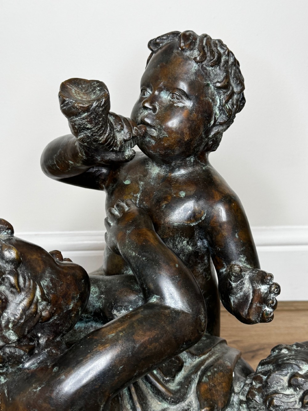A dark patinated French bronze sculptural group depicting three putti playing, with one child blowing into a conch shell. View XI