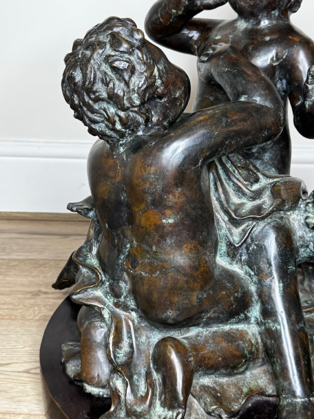 A dark patinated French bronze sculptural group depicting three putti playing, with one child blowing into a conch shell. View XV