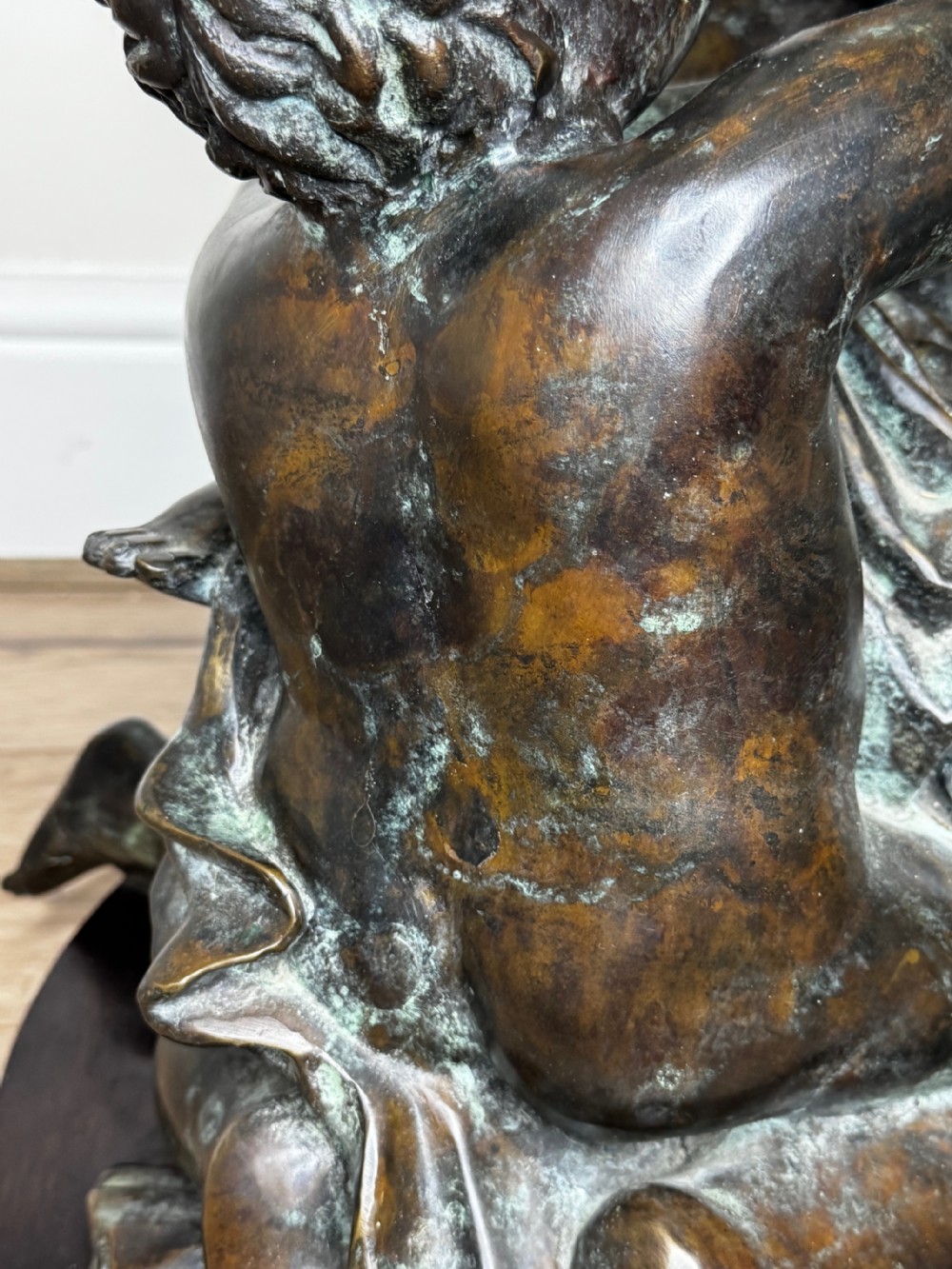 A dark patinated French bronze sculptural group depicting three putti playing, with one child blowing into a conch shell. View XVI